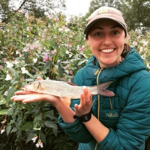 Dr Catie Gutmann Roberts holding a barbel fish by the River Teme