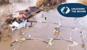 Header image showing the flooding at Diglis Island. The photo shows the locks in the foreground, almost completely submerged underwater, and the waterline level with the white lockkeeper's cottage, as well as red-bricked Diglis Island workshop and old chapel.